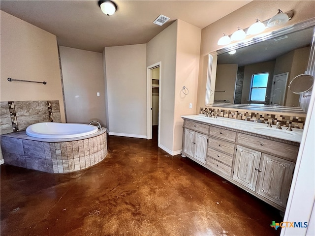 bathroom with concrete flooring, vanity, and a relaxing tiled tub