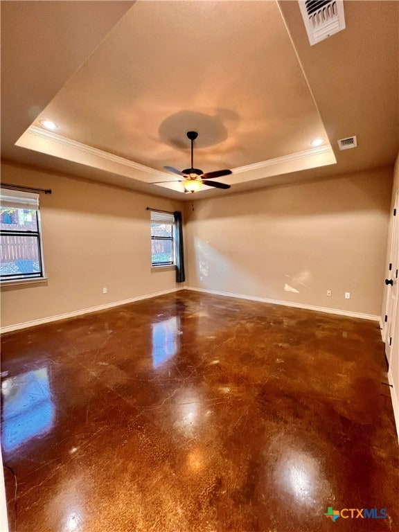 empty room with crown molding, a healthy amount of sunlight, ceiling fan, and a tray ceiling