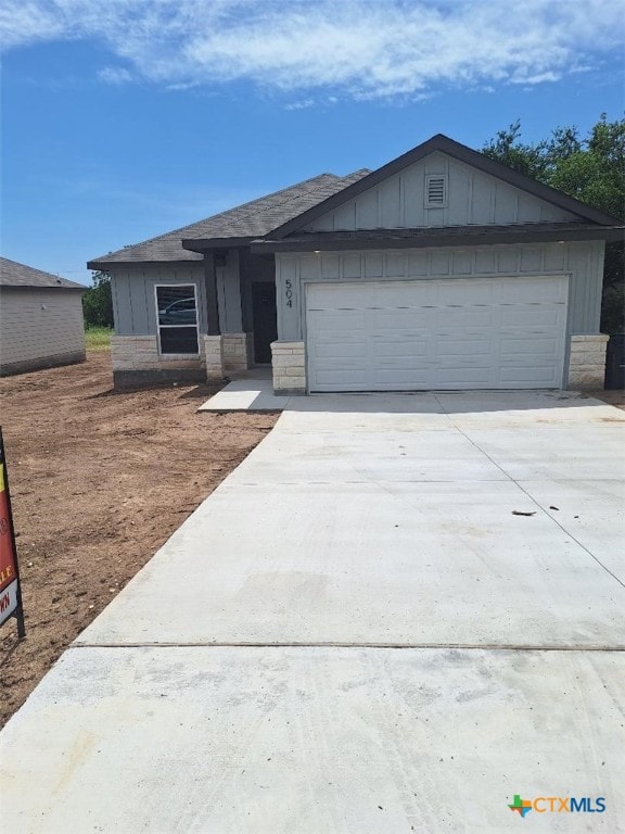 504 Story Ave, Florence, TX 76527 - view of front of home with driveway, board and batten siding, an attached garage, and a shingled roof