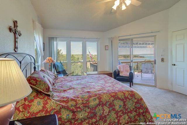 1254 Village Shore Dr, Canyon Lake, TX 78133 - carpeted bedroom featuring access to exterior, vaulted ceiling, and a ceiling fan
