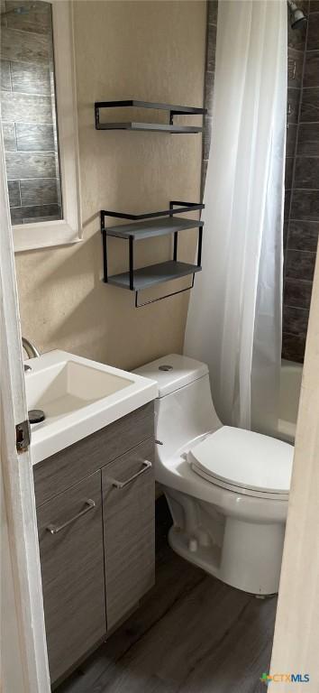 704 E Ave N, Temple, TX 76504 - full bathroom featuring toilet, wood finished floors, vanity, and shower / bath combo with shower curtain