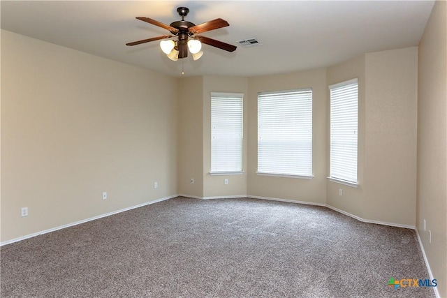 carpeted spare room with a ceiling fan, visible vents, and baseboards