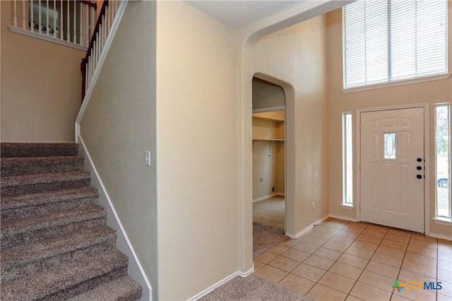 entryway featuring plenty of natural light, light tile patterned flooring, arched walkways, and baseboards