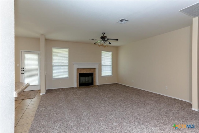 unfurnished living room featuring a ceiling fan, visible vents, a tiled fireplace, and light tile patterned floors