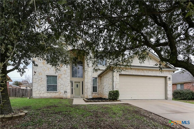 view of front of home featuring concrete driveway, stone siding, an attached garage, fence, and a front yard