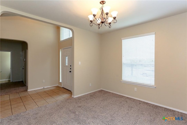 entrance foyer featuring light tile patterned floors, arched walkways, a wealth of natural light, and light colored carpet