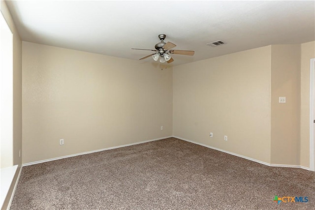 carpeted empty room featuring baseboards, visible vents, and a ceiling fan