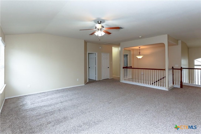 carpeted empty room featuring ceiling fan, lofted ceiling, and baseboards