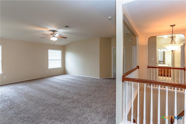 carpeted empty room with a ceiling fan, visible vents, and baseboards