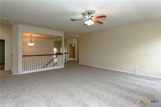 carpeted empty room featuring vaulted ceiling, ceiling fan, and baseboards