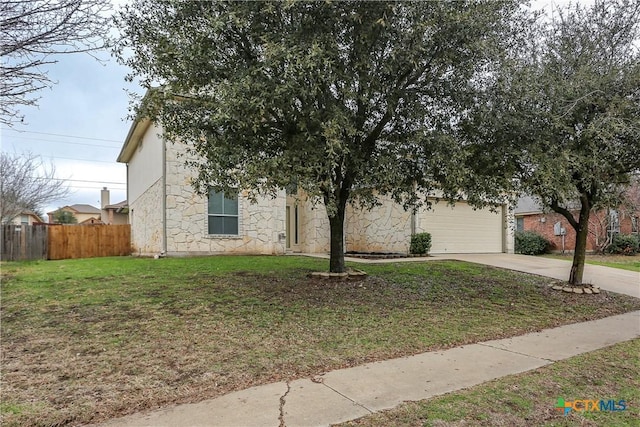 view of property hidden behind natural elements with an attached garage, concrete driveway, a front yard, and fence