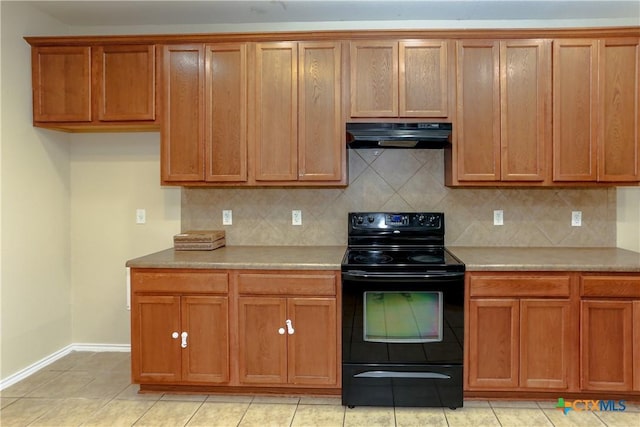 kitchen with brown cabinetry, under cabinet range hood, electric range, and decorative backsplash