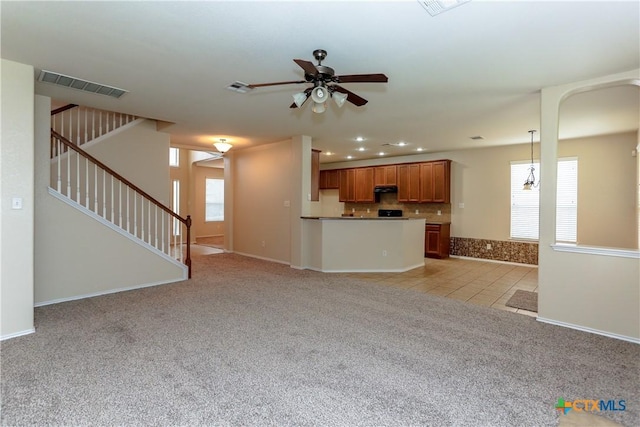 unfurnished living room with light carpet, stairway, visible vents, and a healthy amount of sunlight