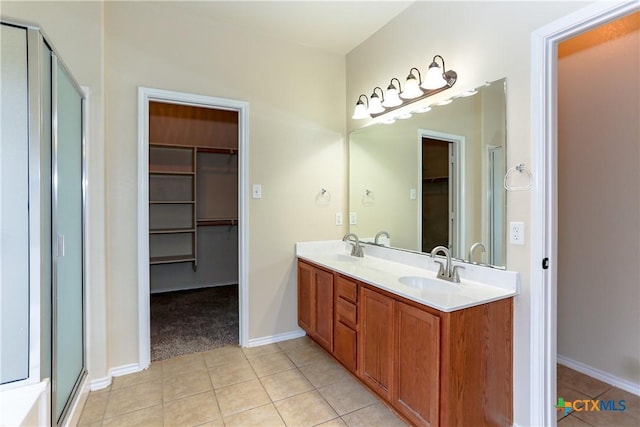 full bath with a sink, a stall shower, tile patterned flooring, and a walk in closet