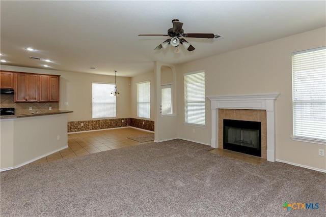 unfurnished living room featuring light tile patterned floors, light colored carpet, a ceiling fan, visible vents, and a tiled fireplace