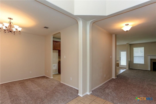 hall with light tile patterned floors, arched walkways, light colored carpet, visible vents, and an inviting chandelier