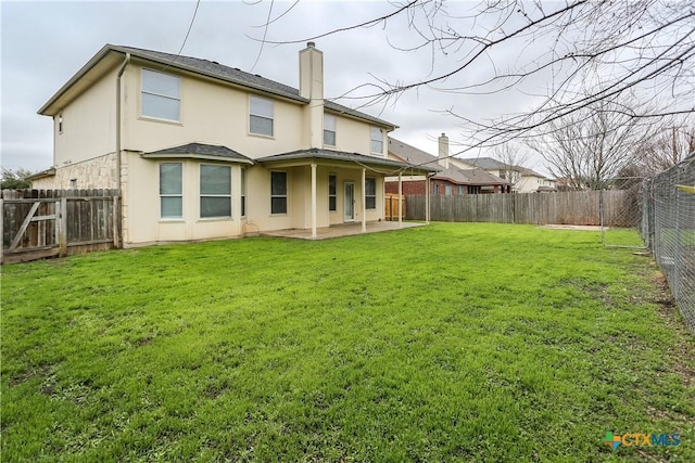 rear view of house featuring a fenced backyard, a yard, stucco siding, a chimney, and a patio area