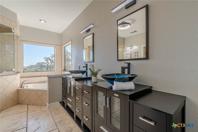 bathroom featuring a relaxing tiled tub and vanity