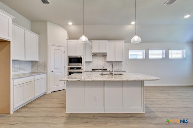 771 Navarro St, New Braunfels, TX 78132 - kitchen featuring stainless steel appliances, white cabinetry, vaulted ceiling, light wood finished floors, and recessed lighting