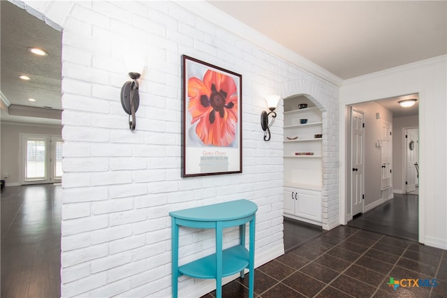 hallway featuring dark hardwood / wood-style floors, brick wall, and ornamental molding