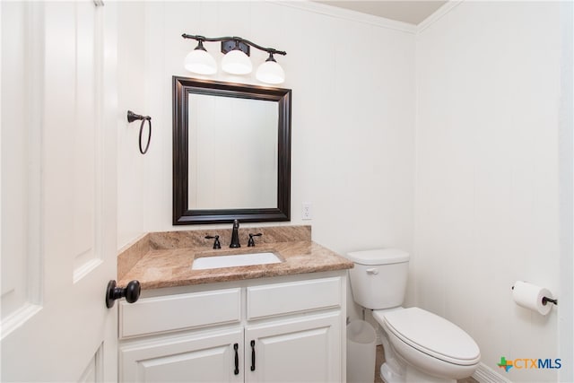 bathroom with toilet, vanity, and crown molding