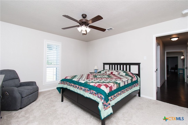 bedroom featuring ceiling fan, a textured ceiling, and light colored carpet