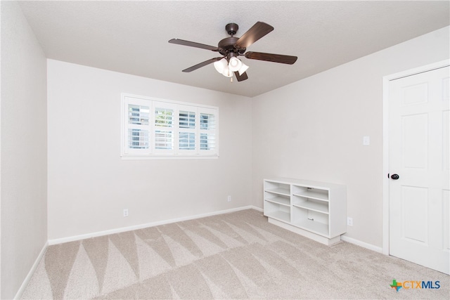 carpeted spare room featuring a textured ceiling and ceiling fan