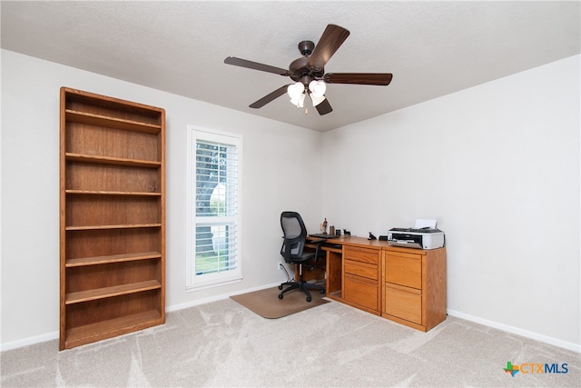 carpeted home office with ceiling fan and a textured ceiling