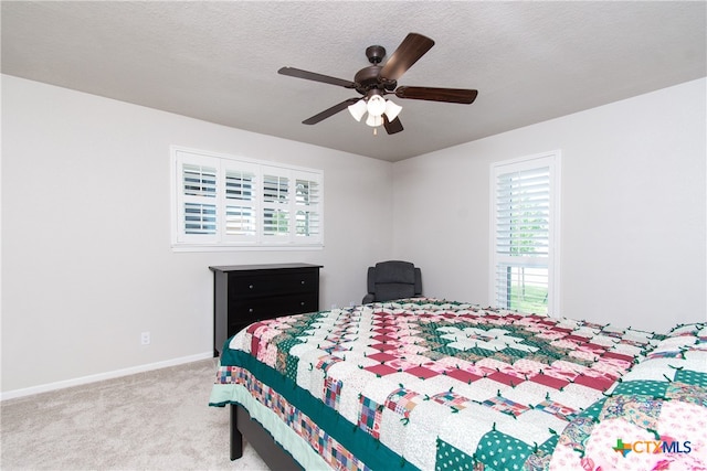 carpeted bedroom with multiple windows, a textured ceiling, and ceiling fan