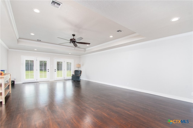 unfurnished living room with ornamental molding, dark hardwood / wood-style flooring, and a tray ceiling