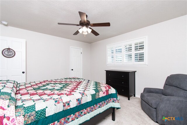 carpeted bedroom with ceiling fan and a textured ceiling