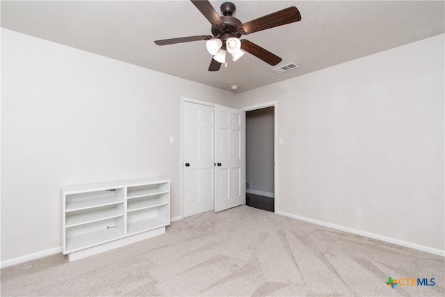 carpeted empty room featuring a textured ceiling and ceiling fan