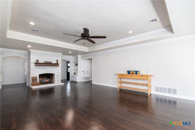 unfurnished living room with dark wood-type flooring, a raised ceiling, and a brick fireplace