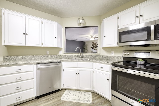4408 Secretariat Dr, Killeen, TX 76549 - kitchen with appliances with stainless steel finishes, a sink, a textured ceiling, white cabinets, and light wood finished floors