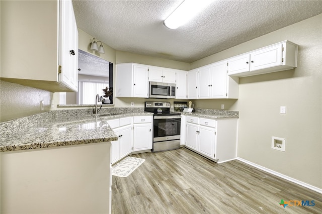 4408 Secretariat Dr, Killeen, TX 76549 - kitchen featuring stainless steel appliances, a sink, a textured ceiling, light wood finished floors, and white cabinets