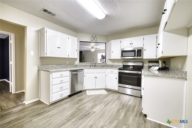 4408 Secretariat Dr, Killeen, TX 76549 - kitchen featuring appliances with stainless steel finishes, light wood-style flooring, a sink, white cabinetry, and a textured ceiling