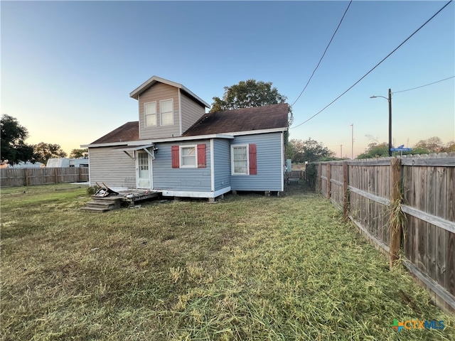 back house at dusk with a lawn