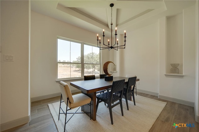 dining area featuring a tray ceiling, a notable chandelier, and light hardwood / wood-style floors