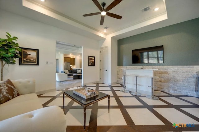 living room with ceiling fan, crown molding, and a tray ceiling