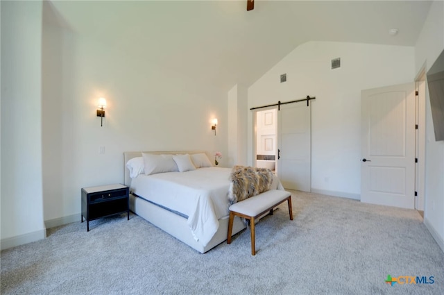 bedroom with a barn door, light carpet, and lofted ceiling