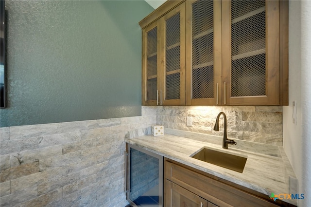 kitchen featuring wine cooler, sink, and light stone counters