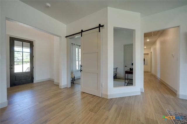 foyer with a barn door and light hardwood / wood-style floors