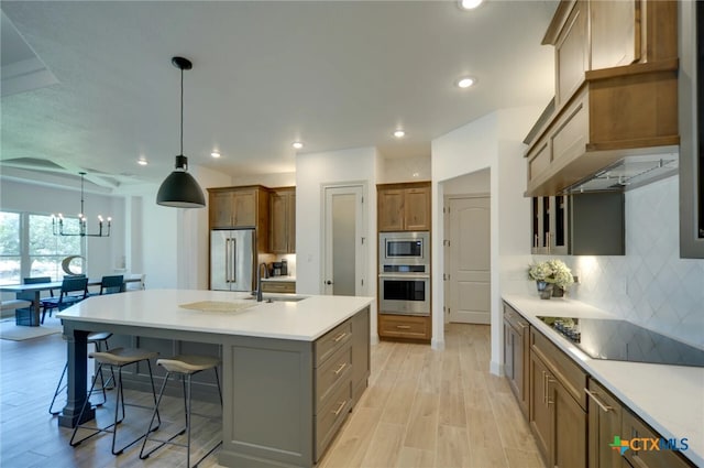 kitchen featuring a center island with sink, sink, a breakfast bar, light wood-type flooring, and appliances with stainless steel finishes