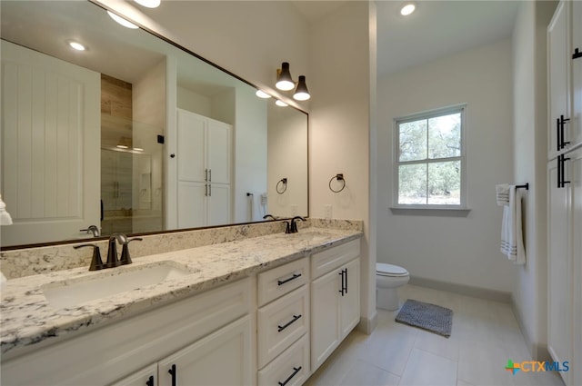 bathroom with a shower with door, vanity, toilet, and tile patterned floors