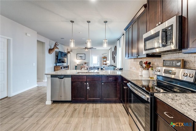 kitchen with a peninsula, appliances with stainless steel finishes, a sink, open floor plan, and decorative backsplash