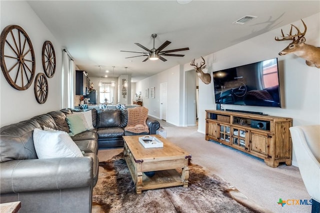 living area featuring light carpet, visible vents, baseboards, and a ceiling fan
