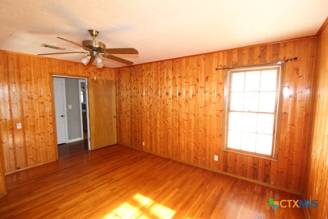 spare room with wood walls, hardwood / wood-style floors, and ceiling fan