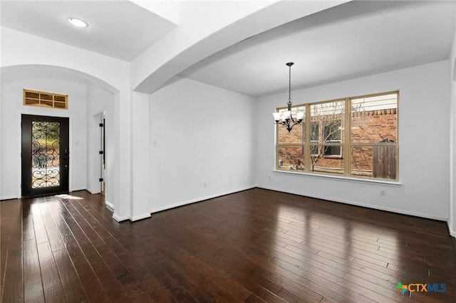 interior space with arched walkways, a chandelier, and dark wood-style flooring