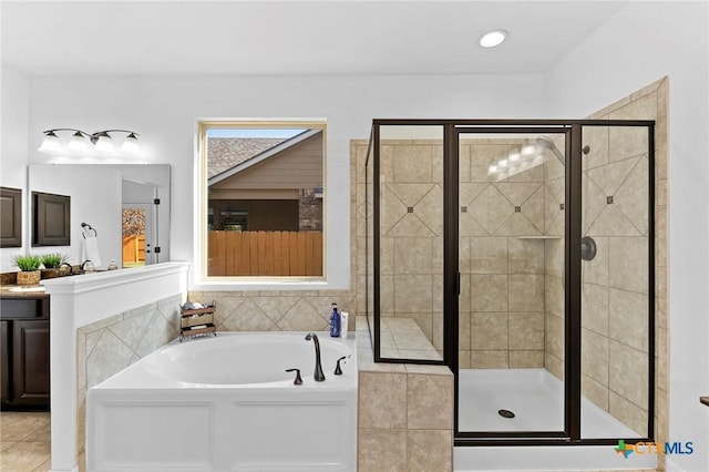 bathroom featuring tile patterned flooring, a shower stall, vanity, and a garden tub