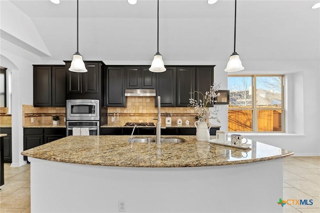 kitchen with light stone countertops, a sink, stainless steel appliances, under cabinet range hood, and backsplash